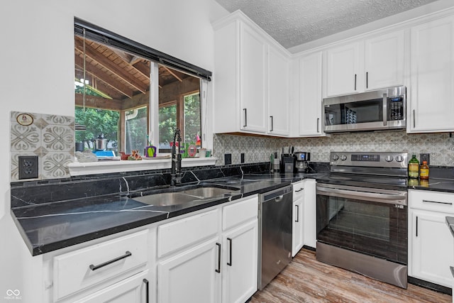 10249 Winlee Ct, Indianapolis, IN 46236 - kitchen featuring appliances with stainless steel finishes, white cabinets, light wood finished floors, decorative backsplash, and a textured ceiling