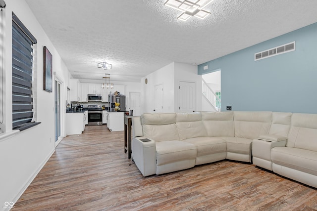 10249 Winlee Ct, Indianapolis, IN 46236 - living area featuring a textured ceiling, a chandelier, and light wood-style floors