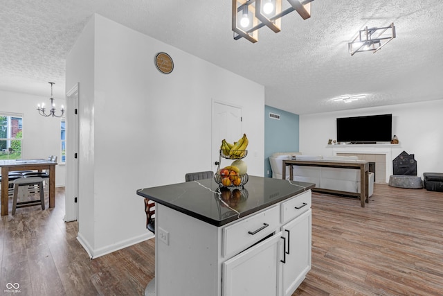 10249 Winlee Ct, Indianapolis, IN 46236 - kitchen featuring a textured ceiling, a chandelier, dark countertops, wood finished floors, and white cabinetry