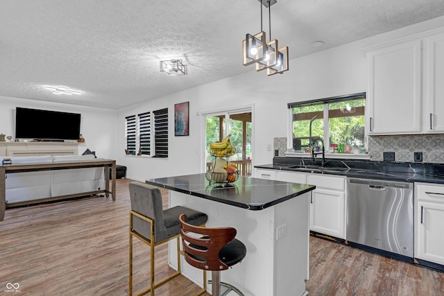 10249 Winlee Ct, Indianapolis, IN 46236 - kitchen with dishwasher, a textured ceiling, light wood-style flooring, dark countertops, and a kitchen breakfast bar