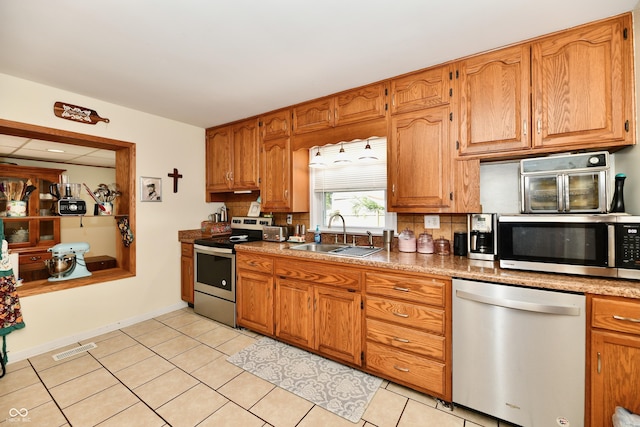 4020 S Lynhurst Dr, Indianapolis, IN 46221 - kitchen with appliances with stainless steel finishes, tasteful backsplash, light tile patterned flooring, and brown cabinets