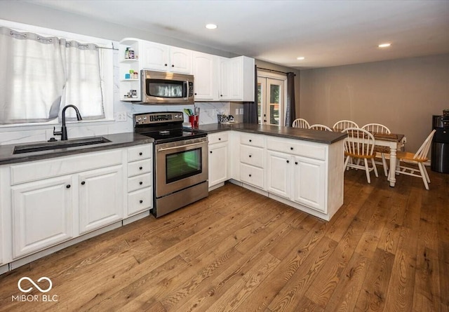 3040 Revere Ct, Columbus, IN 47203 - kitchen with stainless steel appliances, dark countertops, wood finished floors, white cabinets, and recessed lighting