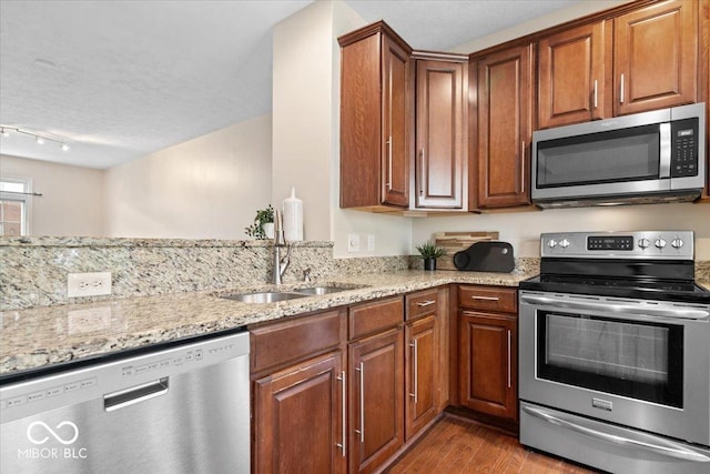 8256 Jo Ellen Dr, Fishers, IN 46038 - kitchen with stainless steel appliances, wood finished floors, light stone countertops, rail lighting, and brown cabinets
