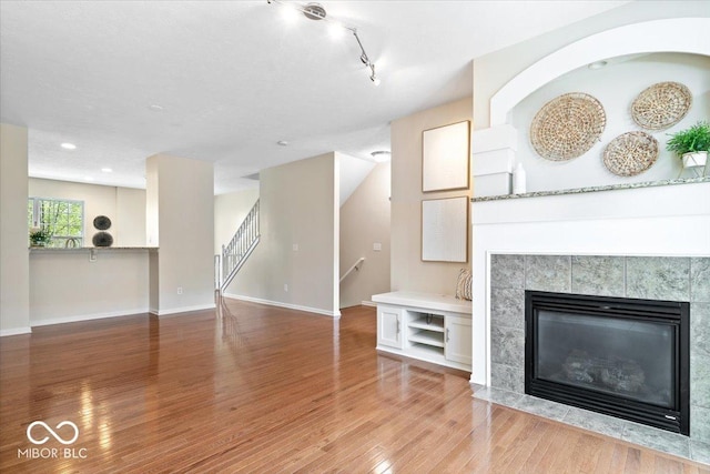 8256 Jo Ellen Dr, Fishers, IN 46038 - unfurnished living room featuring wood finished floors, stairway, a fireplace, rail lighting, and recessed lighting