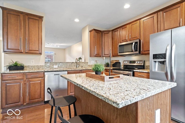 8256 Jo Ellen Dr, Fishers, IN 46038 - kitchen featuring stainless steel appliances, a breakfast bar, light wood-style flooring, light stone countertops, and recessed lighting