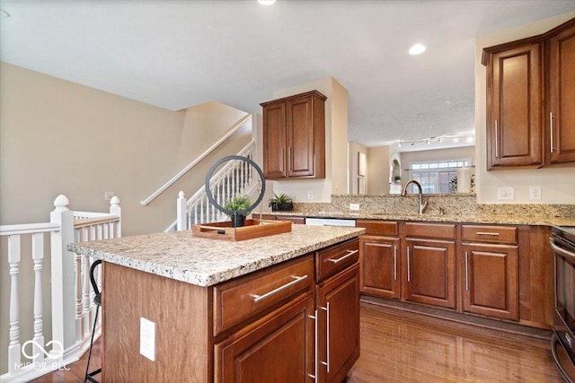 8256 Jo Ellen Dr, Fishers, IN 46038 - kitchen with a kitchen island, wood finished floors, light stone counters, and brown cabinets