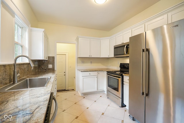 5050 Carrollton Ave, Indianapolis, IN 46205 - kitchen featuring appliances with stainless steel finishes, white cabinets, light stone countertops, and decorative backsplash