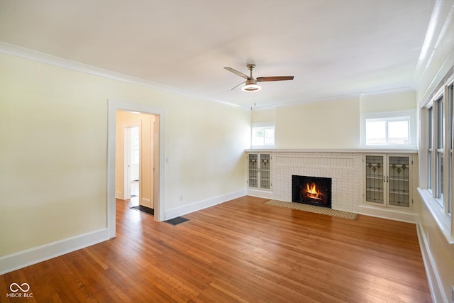 5050 Carrollton Ave, Indianapolis, IN 46205 - unfurnished living room featuring a ceiling fan, wood finished floors, a brick fireplace, and crown molding