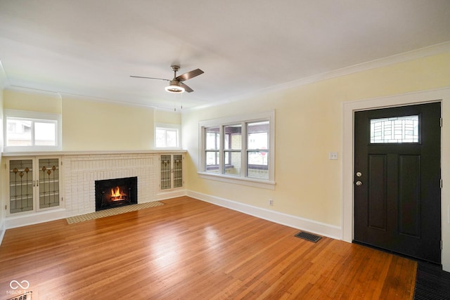 5050 Carrollton Ave, Indianapolis, IN 46205 - unfurnished living room featuring ornamental molding, light wood-style floors, a brick fireplace, and ceiling fan