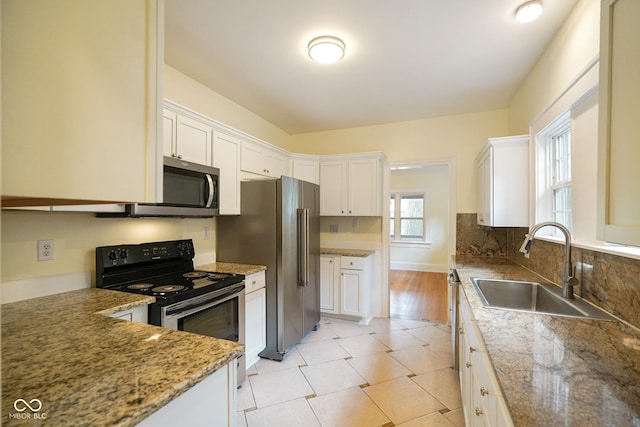 5050 Carrollton Ave, Indianapolis, IN 46205 - kitchen with appliances with stainless steel finishes, white cabinetry, and light stone countertops
