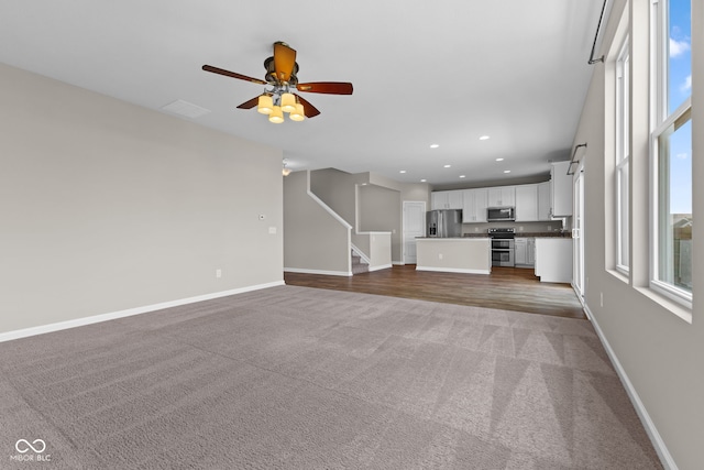 5398 Marigold Dr, Plainfield, IN 46168 - unfurnished living room featuring light colored carpet, a ceiling fan, recessed lighting, and stairs