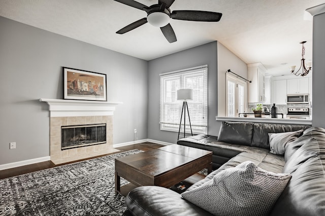12861 Clifford Cir, Carmel, IN 46032 - living area featuring a ceiling fan, a tiled fireplace, dark wood-style floors, and a chandelier