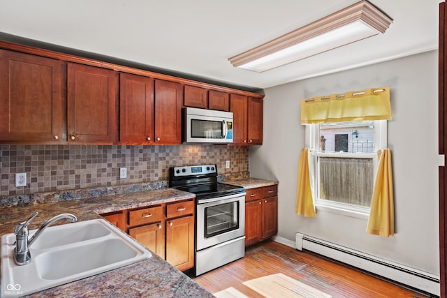 120 W N St, Tipton, IN 46072 - kitchen featuring a baseboard heating unit, appliances with stainless steel finishes, backsplash, light wood finished floors, and brown cabinets
