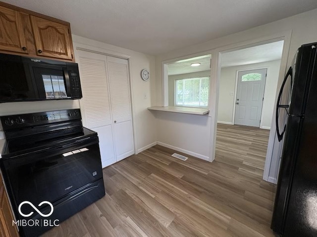 5725 N Clover Maple Dr, Fairland, IN 46126 - kitchen featuring black appliances, wood finished floors, light countertops, and brown cabinetry