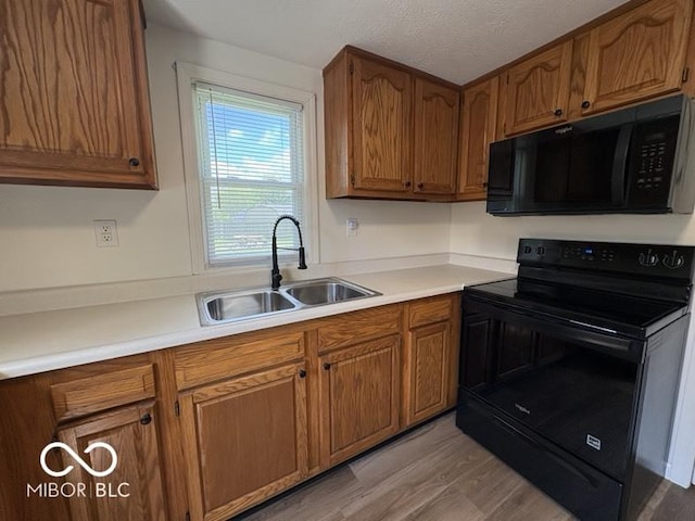 5725 N Clover Maple Dr, Fairland, IN 46126 - kitchen with black appliances, brown cabinetry, light wood-type flooring, and light countertops