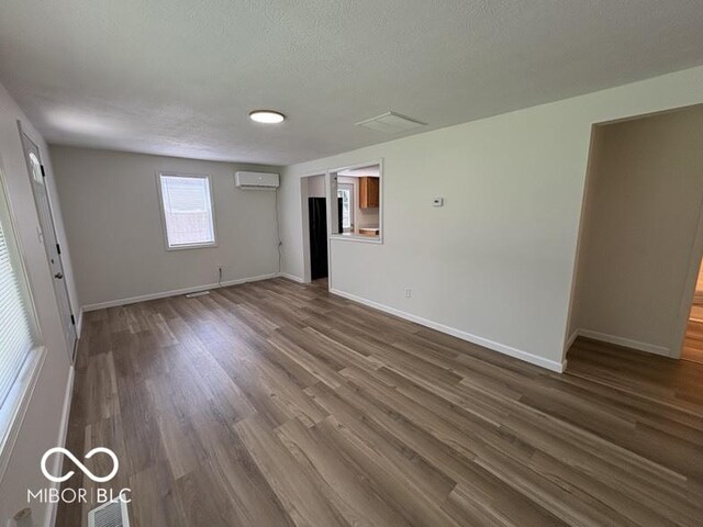 5725 N Clover Maple Dr, Fairland, IN 46126 - unfurnished room with a wall mounted air conditioner, a textured ceiling, and dark wood-type flooring
