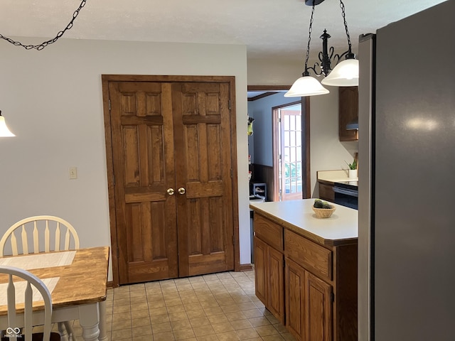 19938 State Road 37 N, Noblesville, IN 46060 - kitchen featuring freestanding refrigerator, light countertops, light tile patterned floors, brown cabinets, and decorative light fixtures