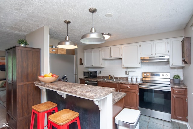 6118 Thrushwood Cir, Indianapolis, IN 46250 - kitchen with stainless steel appliances, under cabinet range hood, decorative backsplash, a breakfast bar, and a textured ceiling
