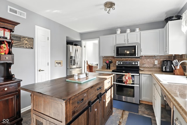 8321 Giroud Way, Indianapolis, IN 46259 - kitchen featuring appliances with stainless steel finishes, tasteful backsplash, a center island, stone finish flooring, and white cabinetry