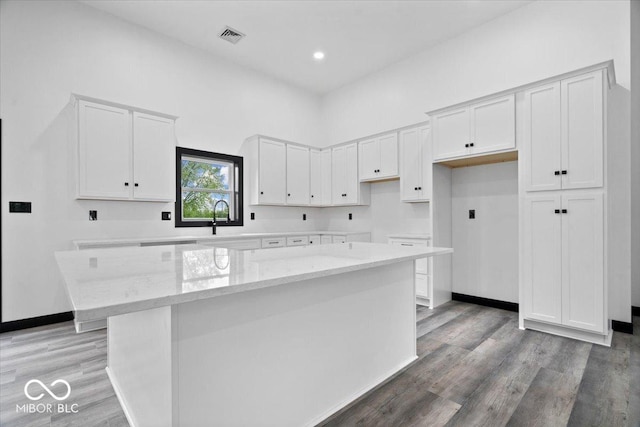 8237 S 100 E, Markleville, IN 46056 - kitchen with a kitchen island, white cabinets, light stone counters, light wood-style flooring, and recessed lighting