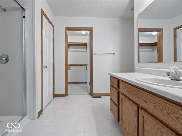 294 Keller Dr, Greenfield, IN 46140 - bathroom with a stall shower, vanity, a spacious closet, a textured ceiling, and tile patterned floors