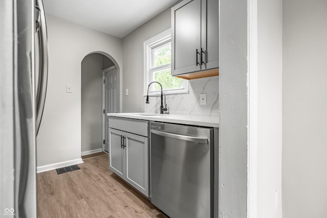 726 N Routiers Ave, Indianapolis, IN 46219 - kitchen with appliances with stainless steel finishes, light wood-type flooring, gray cabinetry, arched walkways, and light countertops
