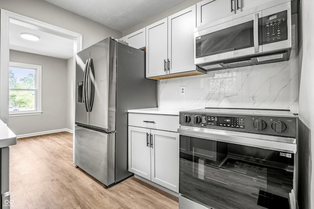 726 N Routiers Ave, Indianapolis, IN 46219 - kitchen with stainless steel appliances, light wood-style flooring, backsplash, light countertops, and white cabinetry