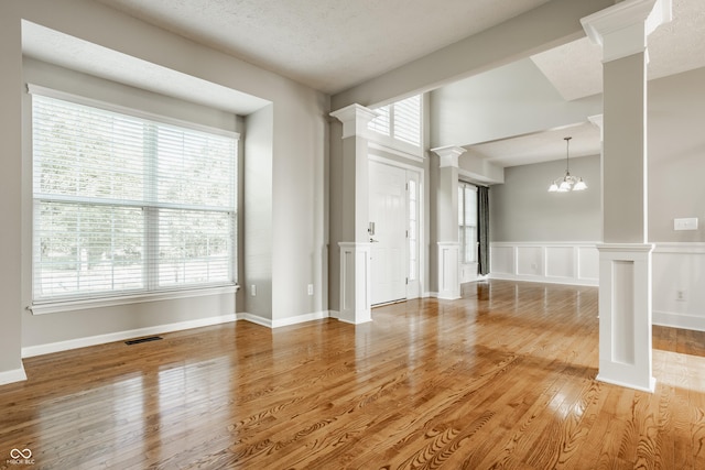 11761 Boothbay Ln, Fishers, IN 46037 - spare room with decorative columns, plenty of natural light, wood finished floors, a chandelier, and a wainscoted wall