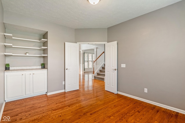 11761 Boothbay Ln, Fishers, IN 46037 - unfurnished room with light wood finished floors, a textured ceiling, and stairs