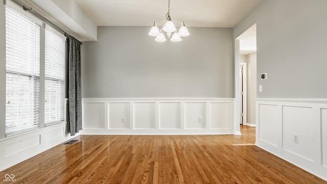 11761 Boothbay Ln, Fishers, IN 46037 - unfurnished dining area featuring a chandelier, wainscoting, wood finished floors, and a decorative wall