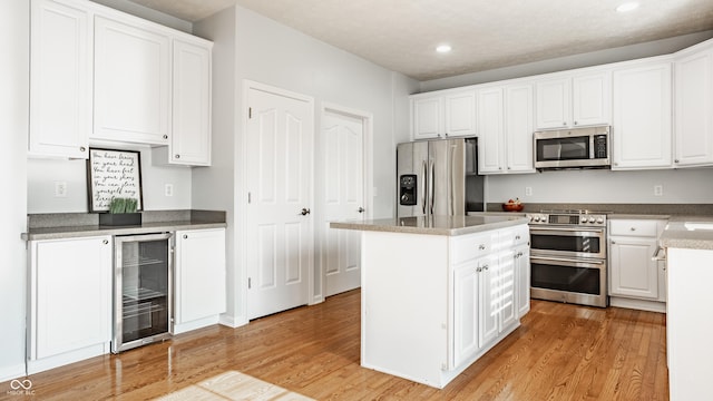 11761 Boothbay Ln, Fishers, IN 46037 - kitchen with stainless steel appliances, wine cooler, light wood-style floors, recessed lighting, and white cabinetry