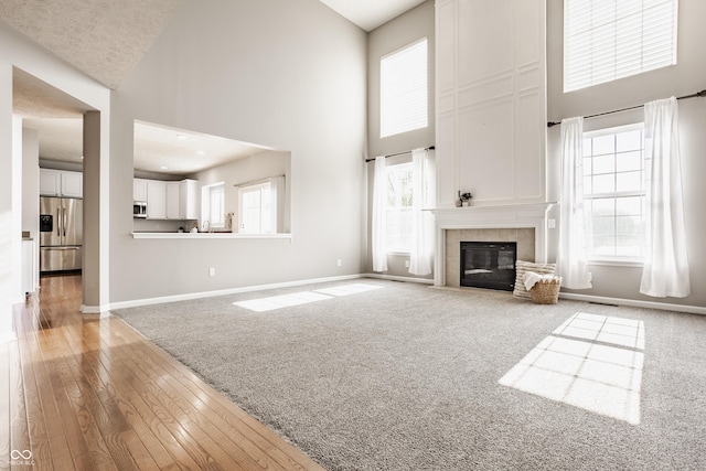 11761 Boothbay Ln, Fishers, IN 46037 - unfurnished living room featuring a high ceiling, a tiled fireplace, wood-type flooring, and carpet floors