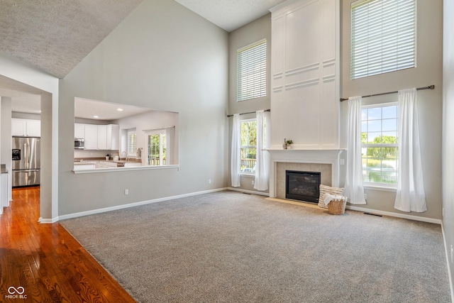 11761 Boothbay Ln, Fishers, IN 46037 - unfurnished living room featuring a towering ceiling, a fireplace, wood finished floors, and carpet floors
