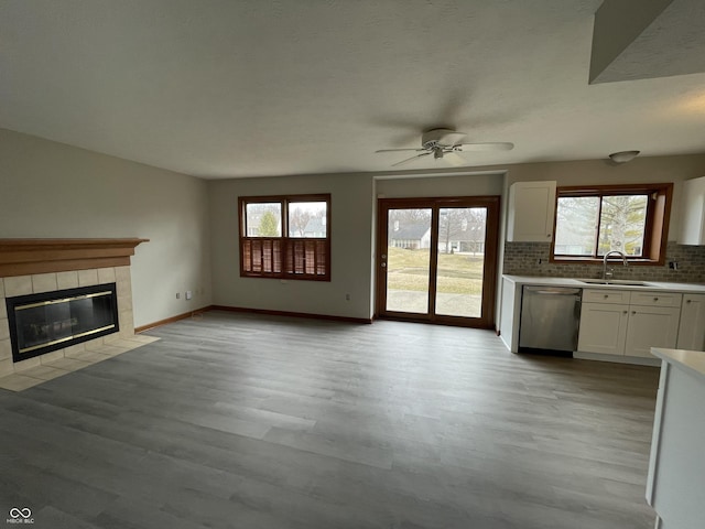 2068 Suda Dr, Carmel, IN 46280 - kitchen featuring dishwasher, ceiling fan, white cabinetry, a tile fireplace, and decorative backsplash