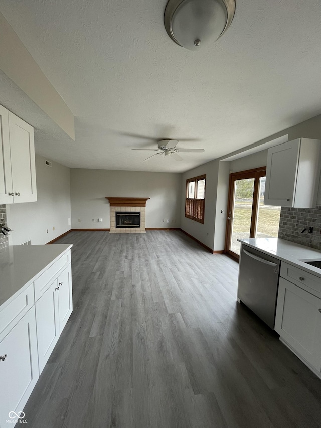2068 Suda Dr, Carmel, IN 46280 - kitchen featuring stainless steel dishwasher, ceiling fan, a tile fireplace, dark wood finished floors, and a textured ceiling
