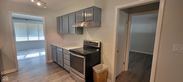2611 Taylor Rd, Columbus, IN 47203 - kitchen with electric stove, gray cabinets, under cabinet range hood, light wood-type flooring, and light countertops