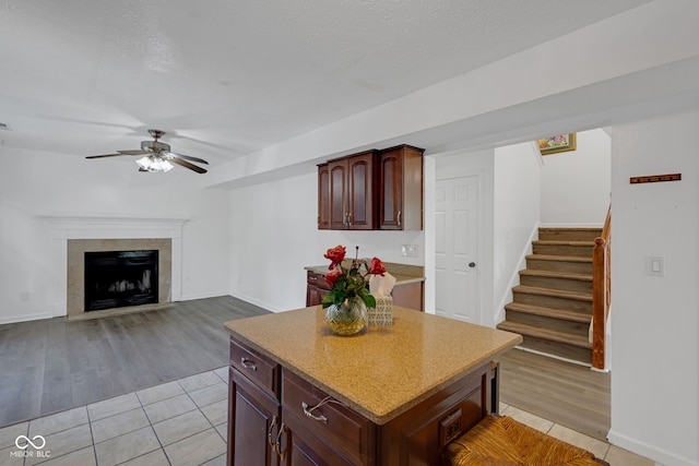8850 Tanner Dr, Fishers, IN 46038 - kitchen featuring ceiling fan, light tile patterned flooring, a kitchen island, and a tile fireplace