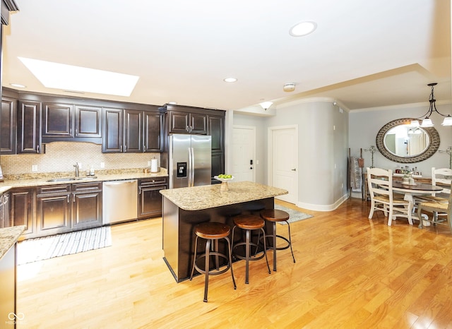 20971 Shoreline Ct Unit 408, Noblesville, IN 46062 - kitchen with appliances with stainless steel finishes, ornamental molding, a kitchen breakfast bar, light wood-style floors, and dark brown cabinets