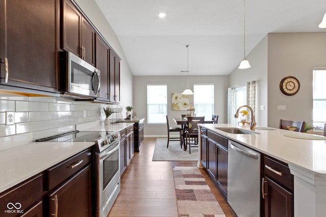 9801 Zion Way, Pendleton, IN 46064 - kitchen featuring stainless steel appliances, vaulted ceiling, wood finished floors, dark brown cabinetry, and hanging light fixtures