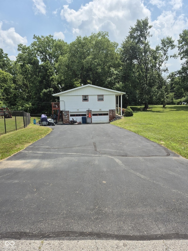 7802 Fall Creek Rd, Indianapolis, IN 46256 - view of front of house with asphalt driveway, a garage, and view of scattered trees
