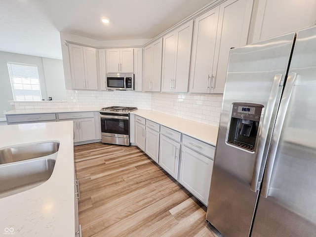 3522 Brampton Ln, Westfield, IN 46074 - kitchen with appliances with stainless steel finishes, light countertops, light wood-type flooring, decorative backsplash, and recessed lighting