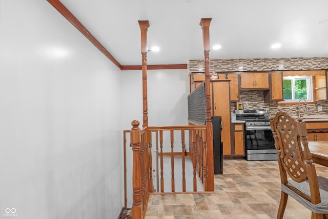 157 E Hill Valley Dr, Indianapolis, IN 46227 - kitchen featuring stainless steel gas range, backsplash, brown cabinets, crown molding, and stone finish floors