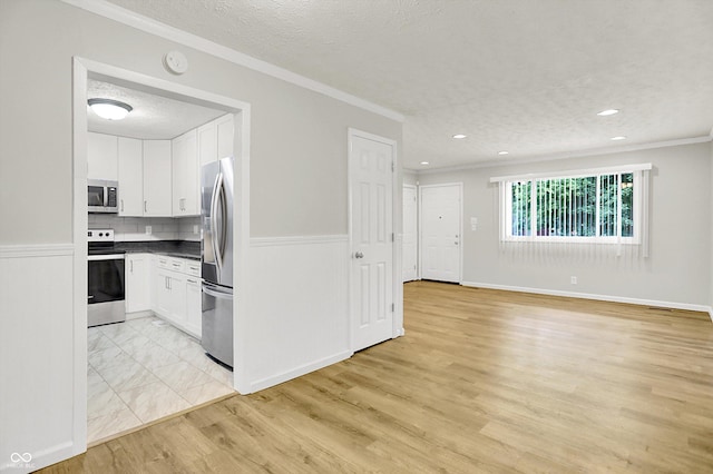 1065 Chevy Chase Ln, Carmel, IN 46280 - kitchen featuring a textured ceiling, white cabinetry, dark countertops, appliances with stainless steel finishes, and ornamental molding