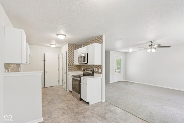 2629 Redland Ln, Indianapolis, IN 46217 - kitchen with appliances with stainless steel finishes, white cabinets, a textured ceiling, ceiling fan, and light colored carpet