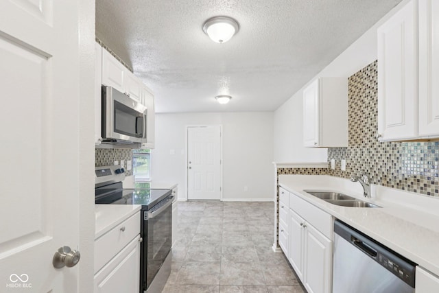 2629 Redland Ln, Indianapolis, IN 46217 - kitchen with appliances with stainless steel finishes, tasteful backsplash, light countertops, white cabinetry, and a textured ceiling