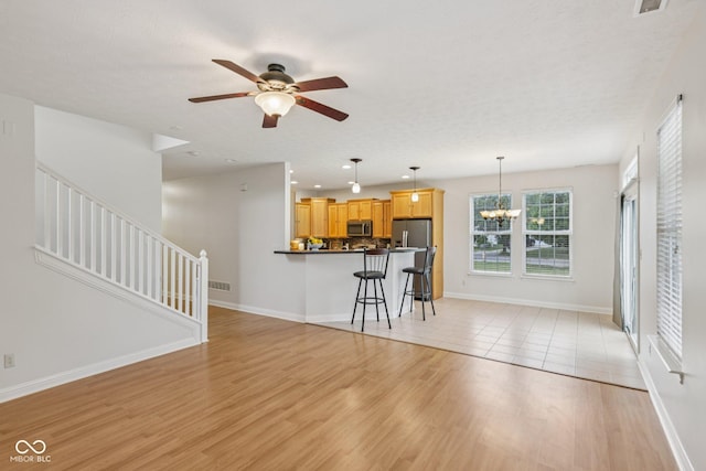 1272 Townsend Dr, Greenwood, IN 46143 - living room featuring ceiling fan, a chandelier, stairs, light wood-type flooring, and recessed lighting