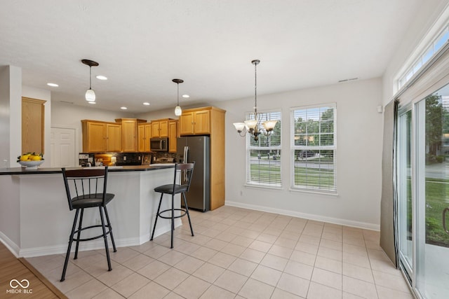 1272 Townsend Dr, Greenwood, IN 46143 - kitchen featuring stainless steel appliances, a peninsula, a chandelier, dark countertops, and a breakfast bar area