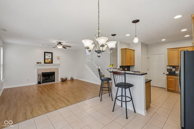 1272 Townsend Dr, Greenwood, IN 46143 - kitchen featuring freestanding refrigerator, a peninsula, ceiling fan, dark countertops, and a breakfast bar area