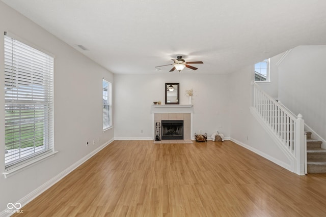 1272 Townsend Dr, Greenwood, IN 46143 - unfurnished living room with stairs, light wood-style floors, a tiled fireplace, and ceiling fan