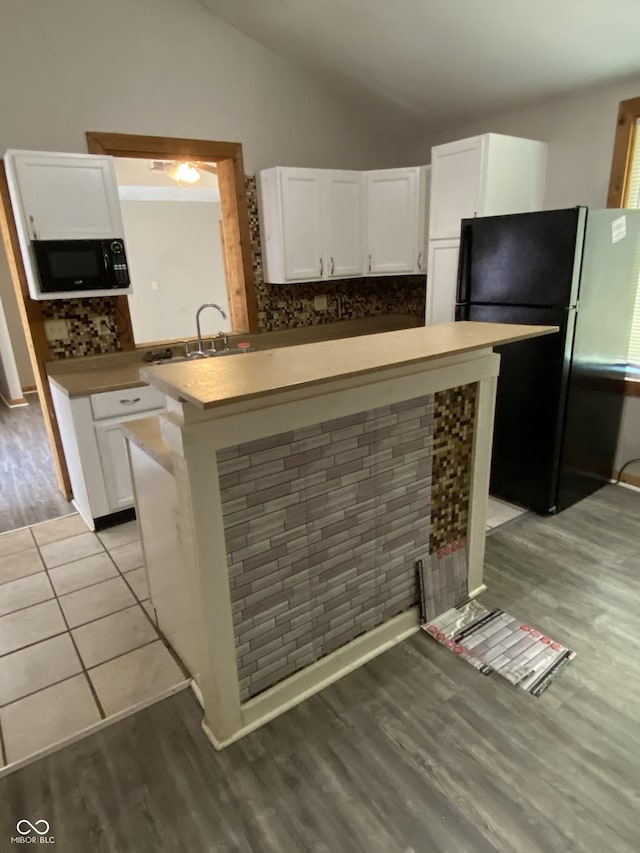 3170 Sapphire Blvd, Indianapolis, IN 46268 - kitchen with black appliances, light wood-type flooring, white cabinetry, lofted ceiling, and decorative backsplash